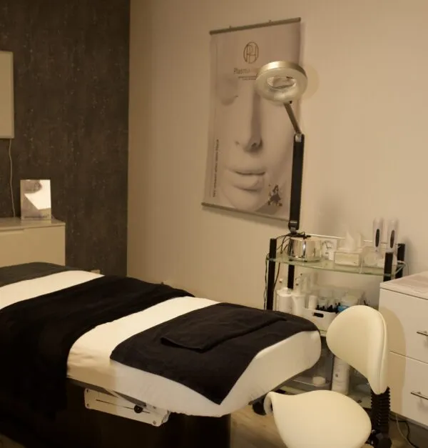Behandlungsraum eines Partnerstudios mit Liege und Plasma-Health-Plakaten